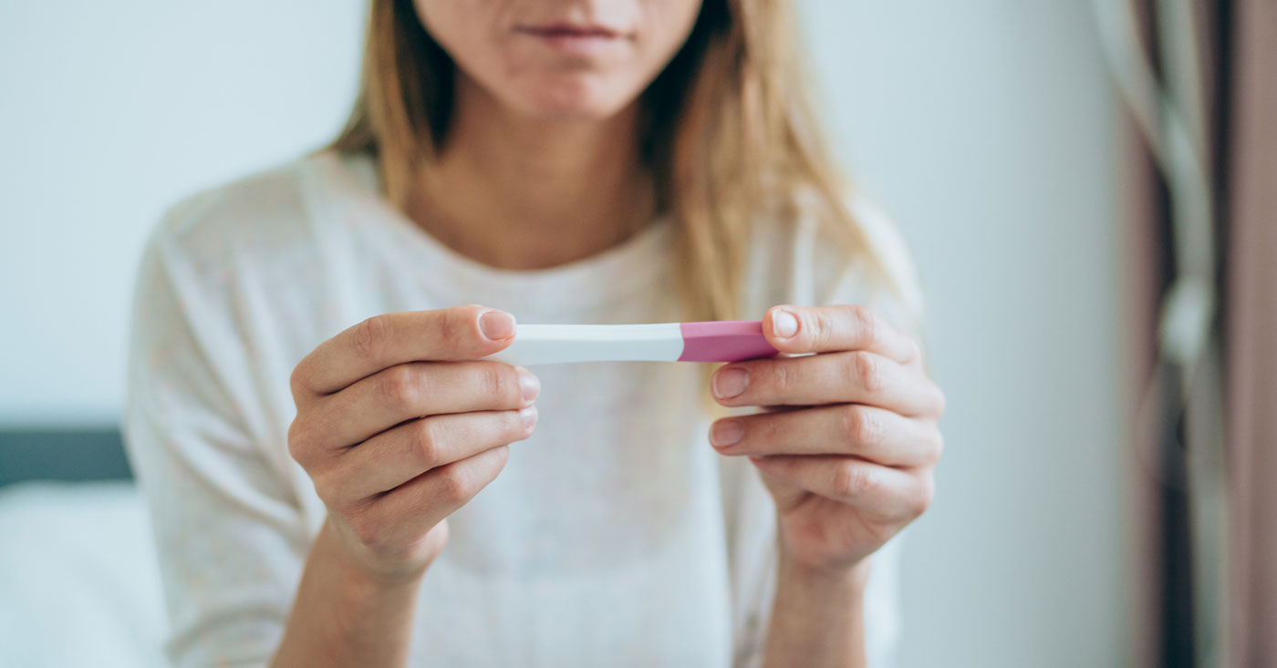 Woman holding pregnancy test.