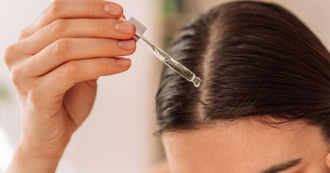 Woman using topical hair treatment.