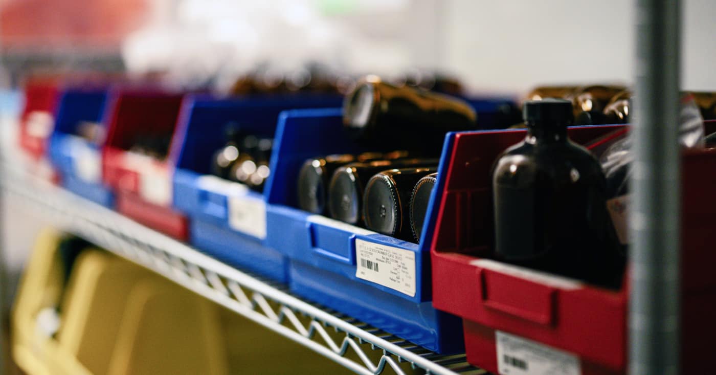Blue And Red Storage Bins With Labeled Parts On Warehouse Shelf