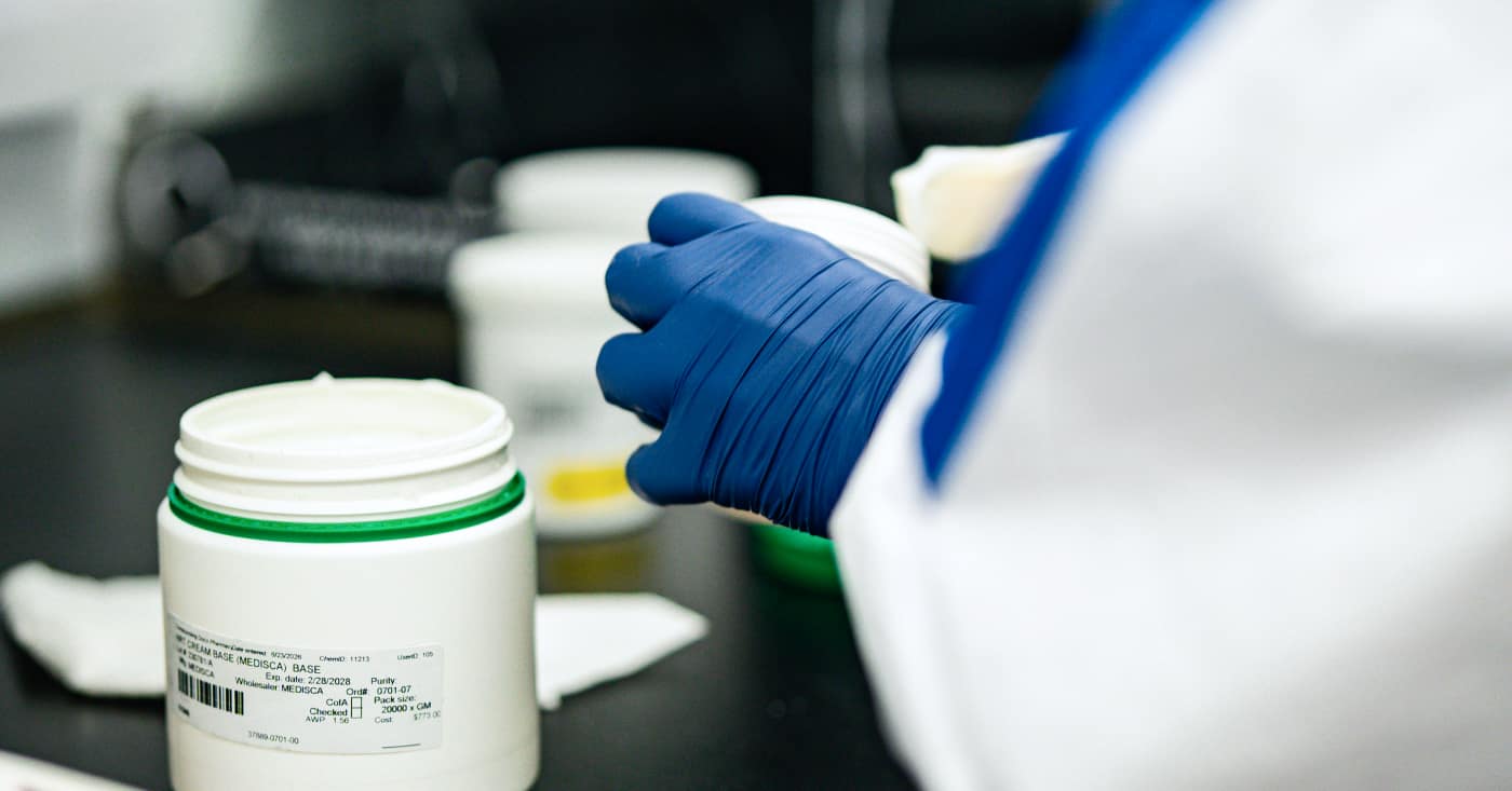 Lab Technician Handling Labeled Chemical Container Wearing Blue Gloves