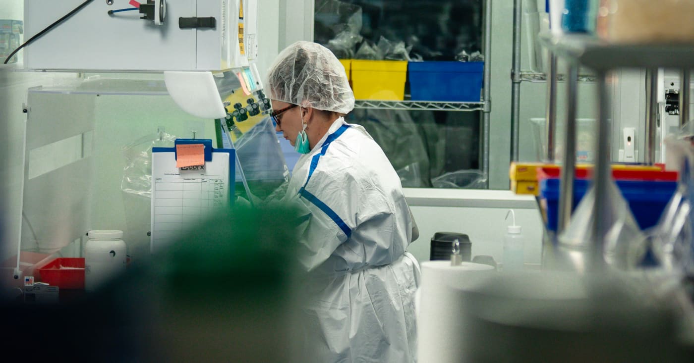 Lab Technician Working In Biosafety Cabinet Wearing Protective Gear